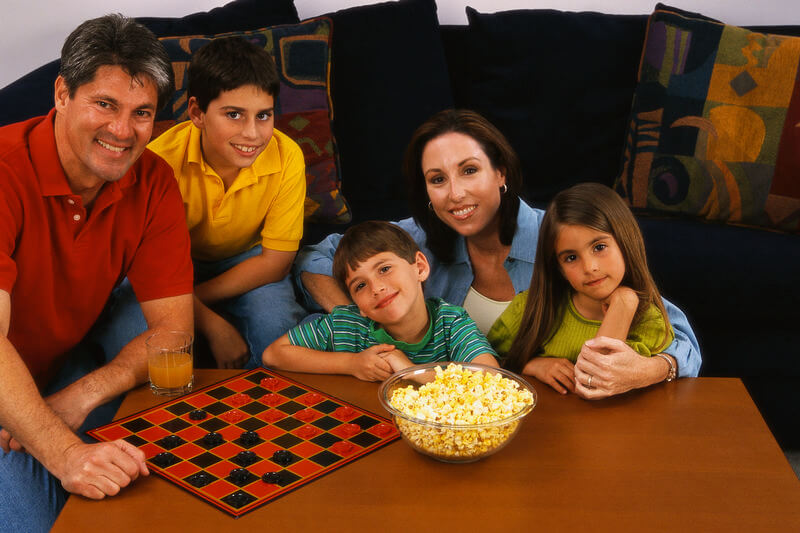 a family with checkers and a checker board and a bowl of popcorn